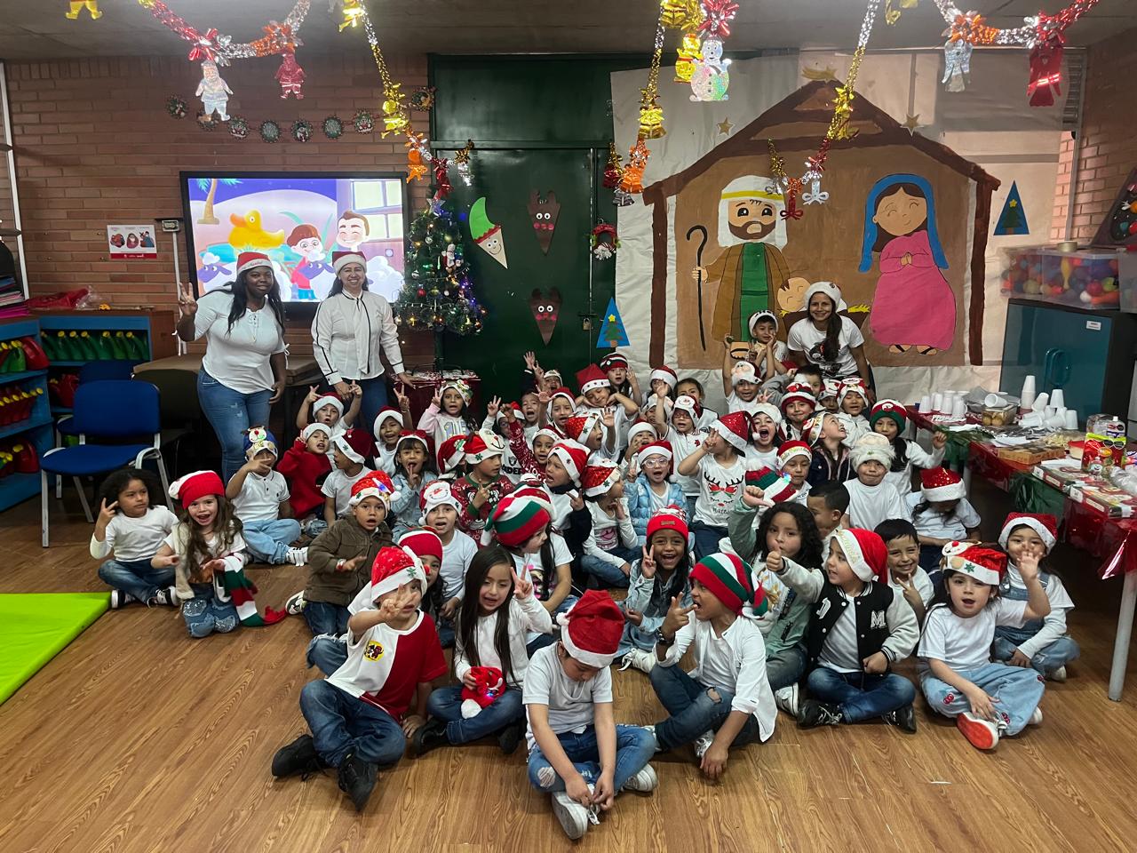Niños de preescolar con gorrito navideño acompañados de sus profesoras 